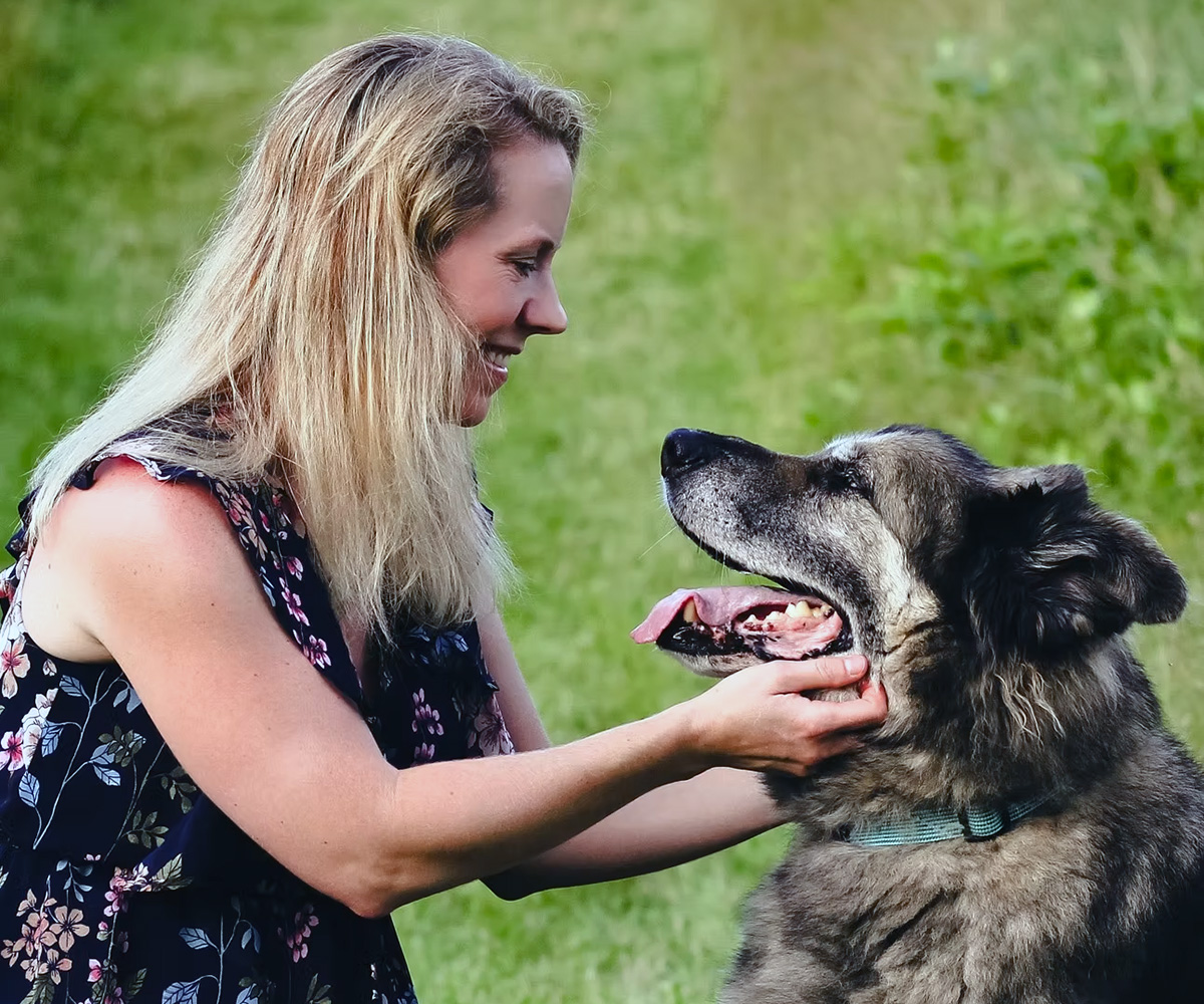 Dr. Sarena gently comforting a happy senior dog outdoors, representing compassionate pet care with Peace for Paws in Las Vegas